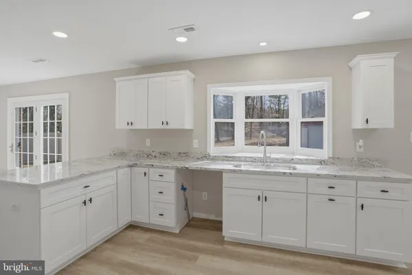 a large white kitchen with granite countertop a sink and dishwasher with a large window
