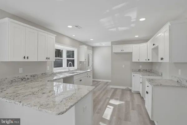 a kitchen with granite countertop a sink and white cabinets