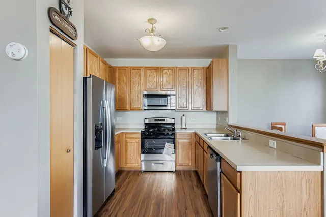 a kitchen with a refrigerator a stove top oven a sink and dishwasher with wooden floor