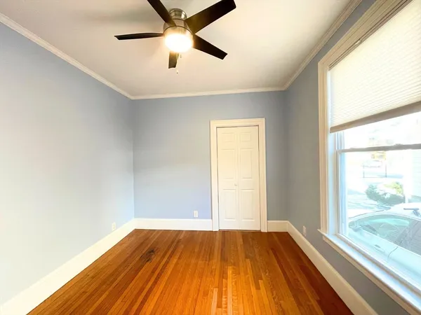a view of empty room with wooden floor and fan