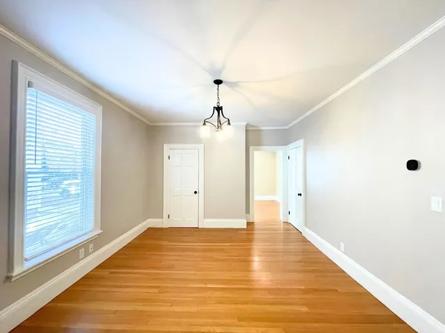 a view of an empty room with window and wooden floor