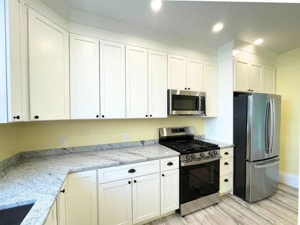 a kitchen with stainless steel appliances granite countertop a stove a refrigerator and a microwave