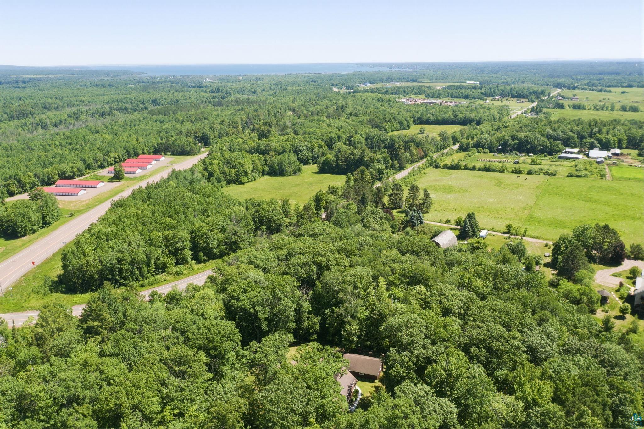27485 South Kane Road Ashland, WI 54806 - Photo 32 of 35 Expansive property featuring abundant mature trees, open green fields, and distant structures with red roofs