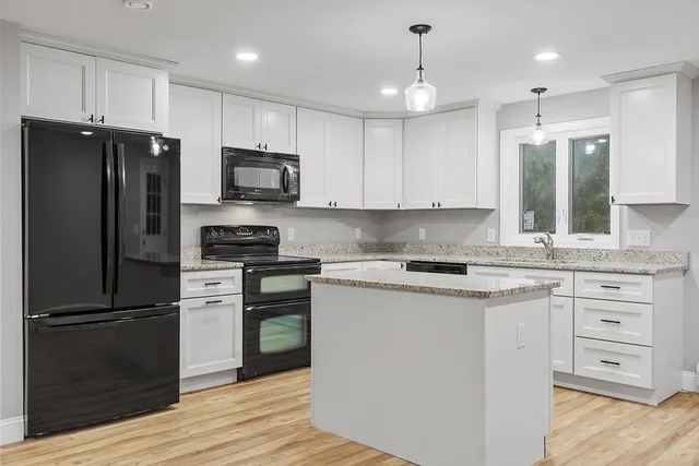 a kitchen with cabinets stainless steel appliances and wooden floor