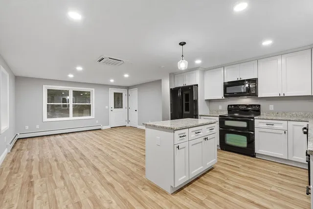 a kitchen with stainless steel appliances granite countertop a stove top oven a sink dishwasher a refrigerator and a oven with wooden floors