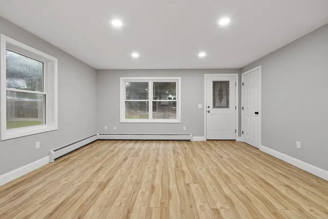 a view of an empty room with wooden floor and a window