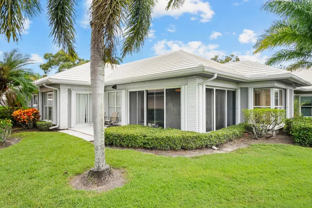 a view of a house with a yard and palm trees