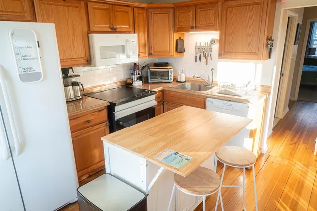 a kitchen with stainless steel appliances a refrigerator a sink a stove and white cabinets