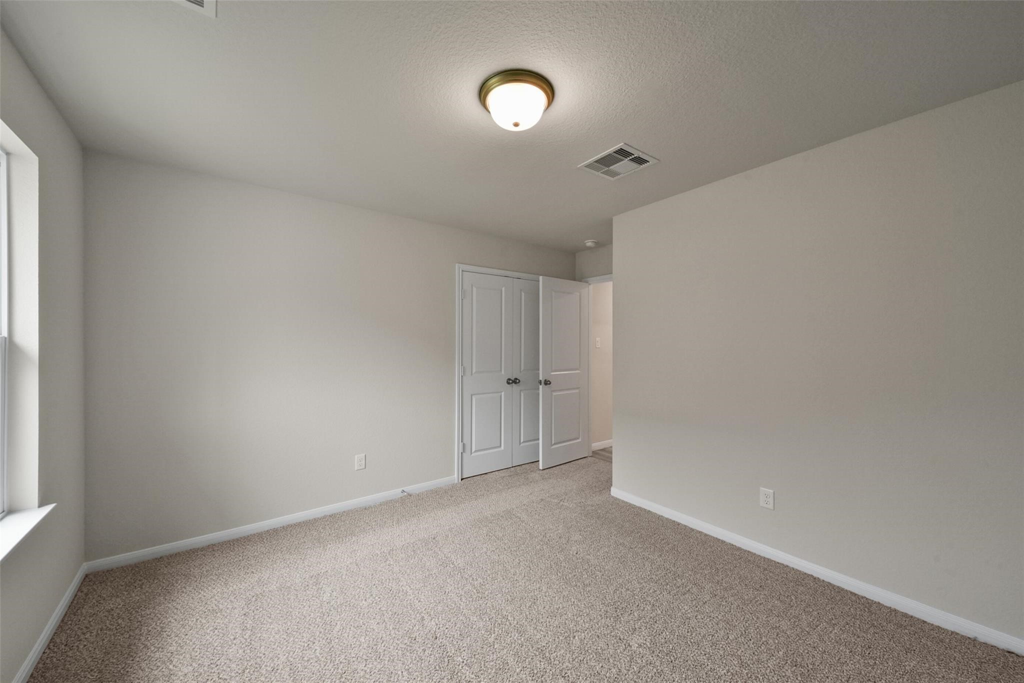 10522 Plumas Run Drive Rosharon, TX 77583 - Photo 17 of 29 Bright, carpeted room featuring a double-door closet, neutral tones, and ample natural light.