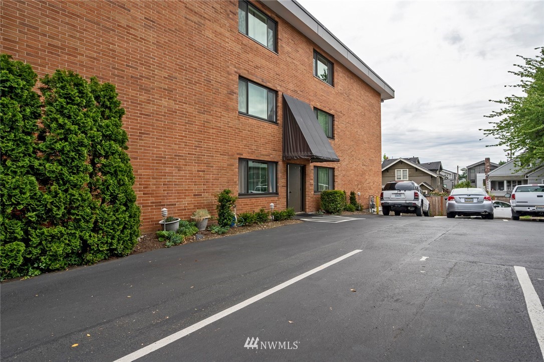 911 North 73rd Street, Unit 407 Seattle, WA 98103 - Photo 26 of 27 a car parked in front of a brick house with a small yard