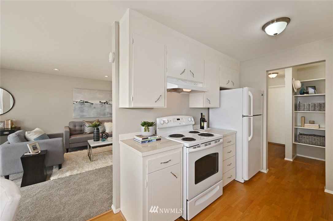 911 North 73rd Street, Unit 407 Seattle, WA 98103 - Photo 9 of 27 a kitchen with stainless steel appliances a stove a refrigerator a sink a stove and white cabinets