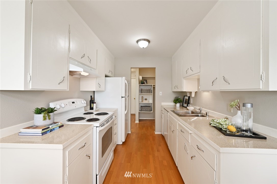 911 North 73rd Street, Unit 407 Seattle, WA 98103 - Photo 10 of 27 a kitchen that has a lot of cabinets a sink and appliances