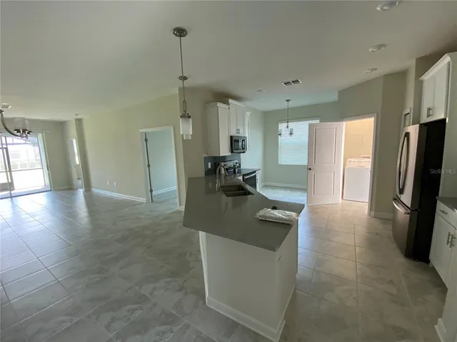 a kitchen with stainless steel appliances granite countertop a refrigerator a sink a stove and a refrigerator