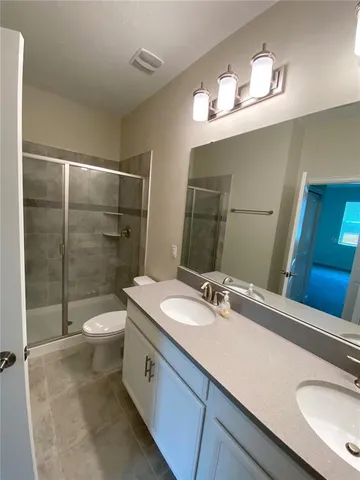 a bathroom with a sink a toilet a mirror and shower