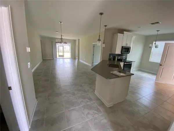 a living room with couches and kitchen view with wooden floor