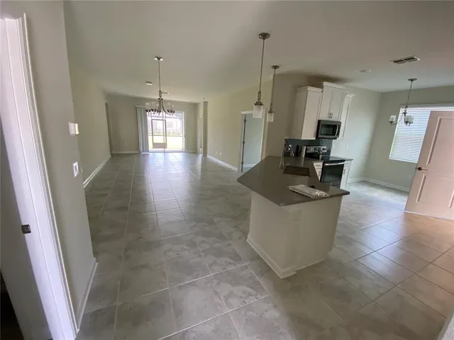 a living room with couches and kitchen view with wooden floor