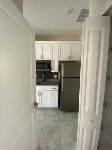 a kitchen with a refrigerator a stove top oven and white cabinets