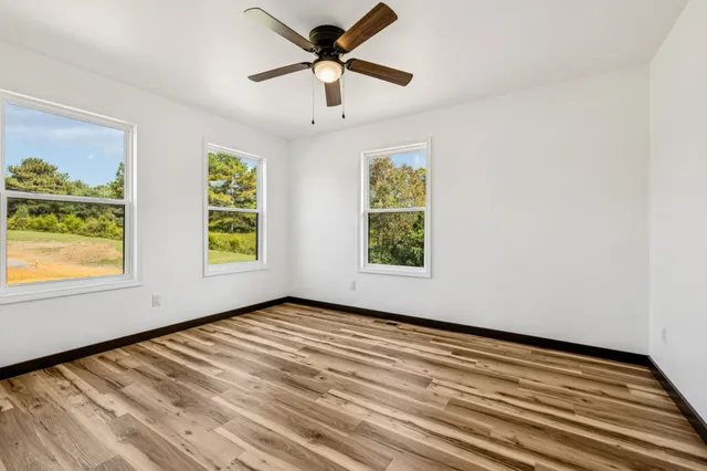 a view of empty room with wooden floor and fan