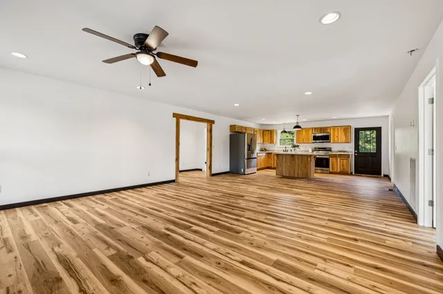 a view of a room with a ceiling fan hardwood floor and a ceiling fan