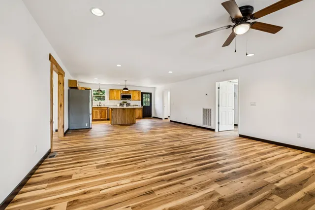 a view of an empty room with wooden floor and windows
