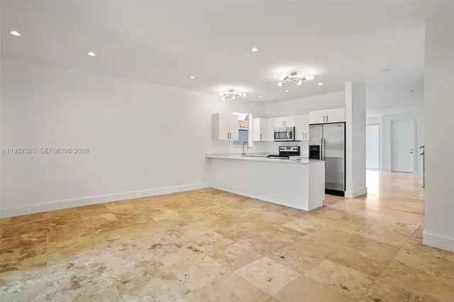 a view of kitchen with kitchen island granite countertop stainless steel appliances refrigerator sink and cabinets