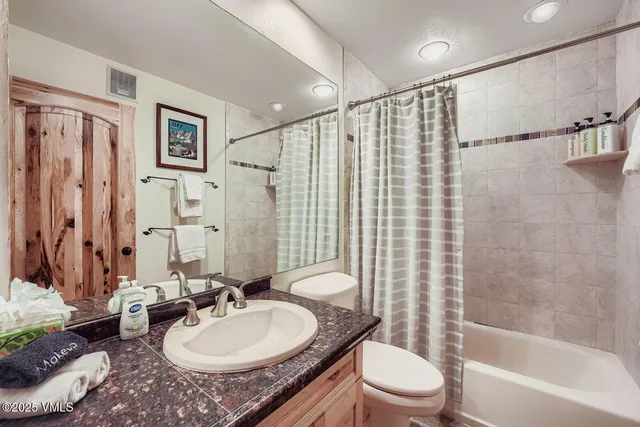 a bathroom with a granite countertop sink toilet a mirror a bathtub and shower