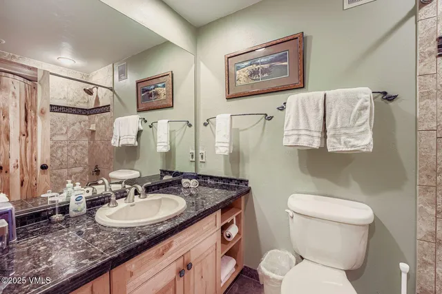 a bathroom with a granite countertop sink toilet and a mirror