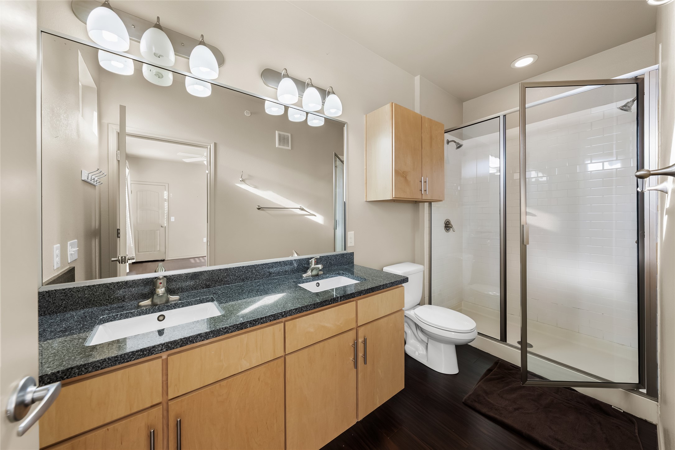 2606 Wilson Street, Unit 901 Austin, TX 78704 - Photo 23 of 37 a bathroom with a granite countertop sink a toilet a mirror and shower