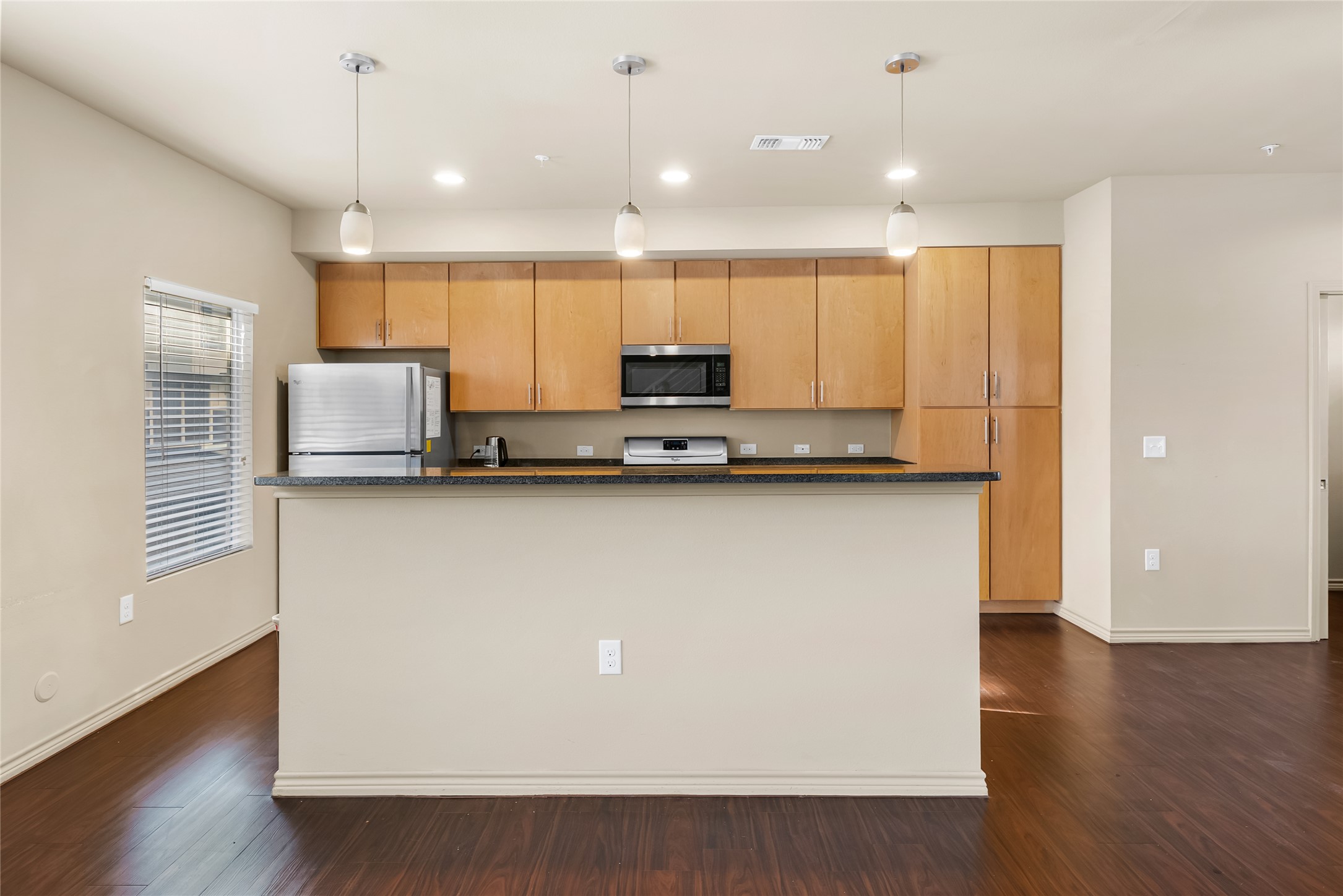 2606 Wilson Street, Unit 901 Austin, TX 78704 - Photo 9 of 37 a kitchen with kitchen island granite countertop a sink a counter space and a refrigerator