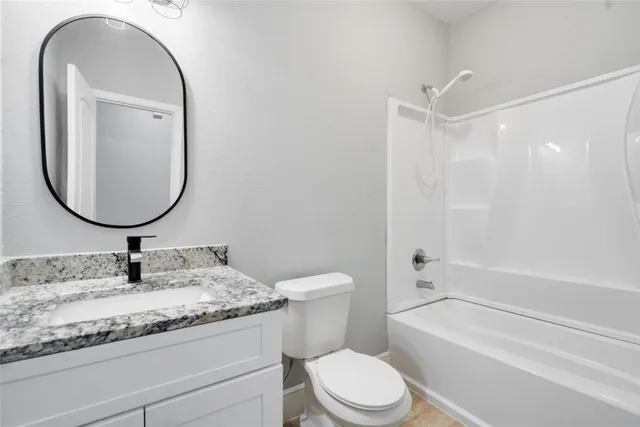 a bathroom with a granite countertop toilet a sink and a mirror
