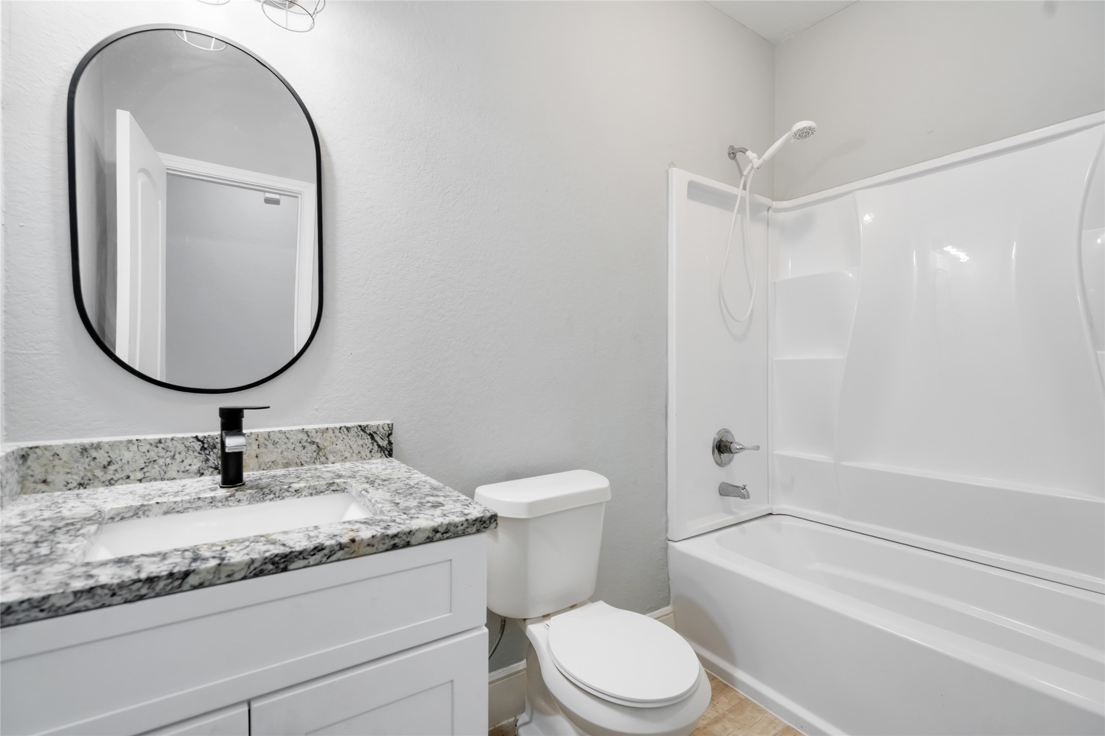 5754 Reed Road, Unit B Houston, TX 77033 - Photo 20 of 29 a bathroom with a granite countertop toilet a sink and a mirror