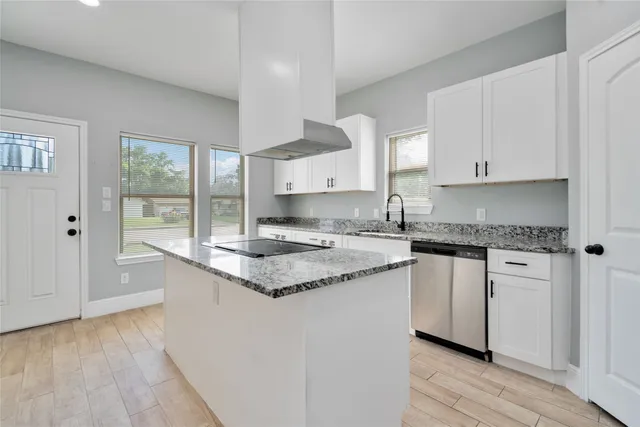a kitchen with granite countertop a sink cabinets and wooden floor