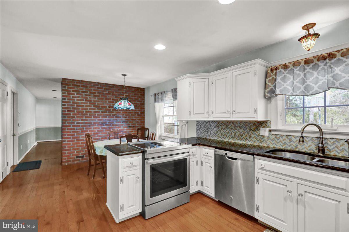561 Millcross Road Lancaster, PA 17601 - Photo 11 of 52 a kitchen with stainless steel appliances granite countertop a stove a sink dishwasher and white cabinets with wooden floor