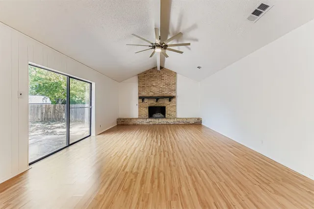 a view of empty room with wooden floor and fireplace