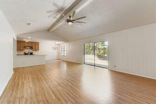 a view of an empty room with a window and wooden floor