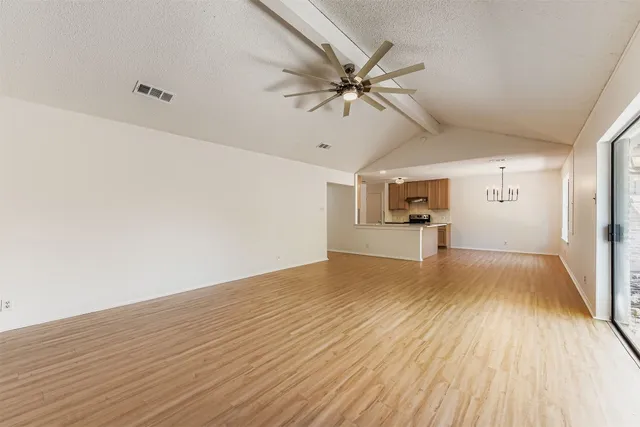 a view of a room with wooden floor a ceiling fan and windows
