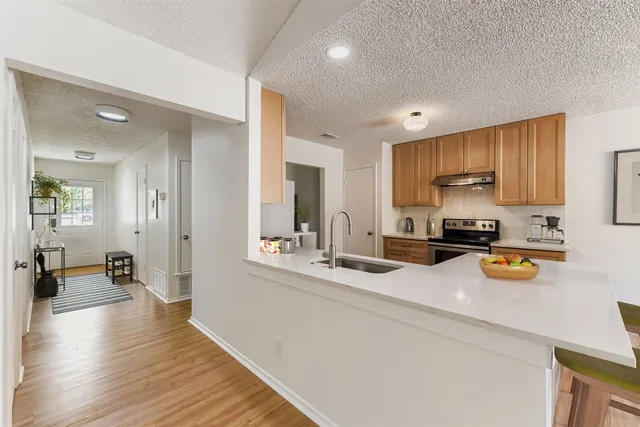 a kitchen with a refrigerator a stove and a sink with wooden floor