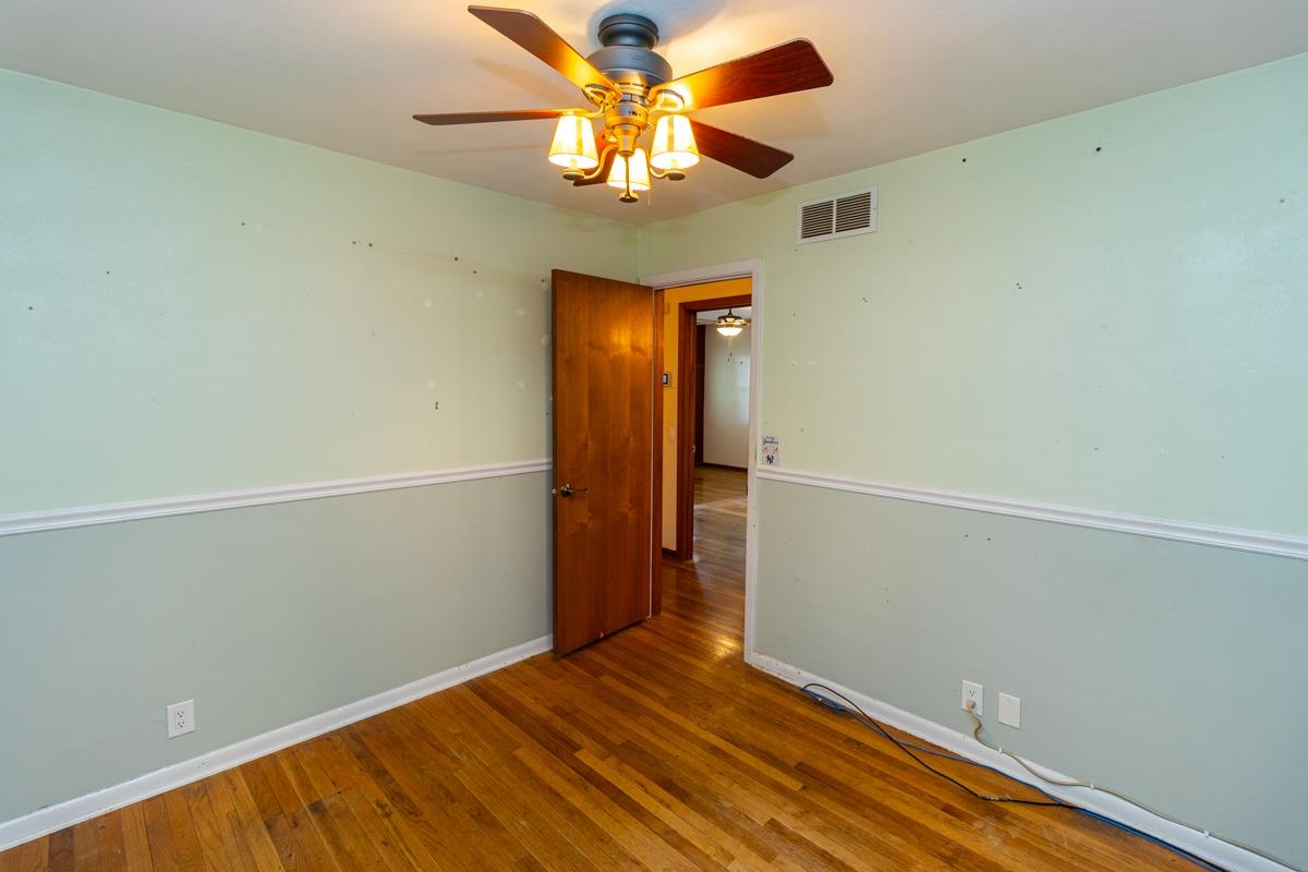 3096 East Water Road Byron, IL 61010 - Photo 10 of 29 an empty room with a chandelier fan and wooden floor