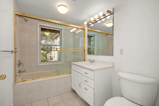 a bathroom with a granite countertop sink toilet tub and mirror