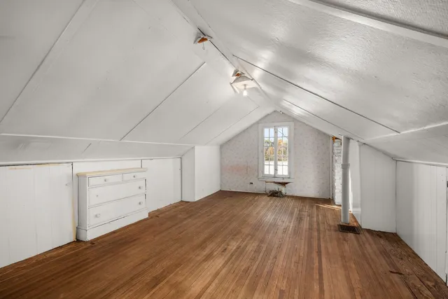 a view of empty room with wooden floor and window