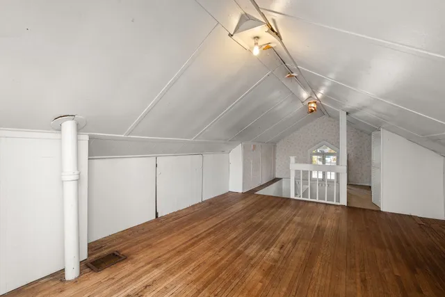 a big room with wooden floor closet and windows