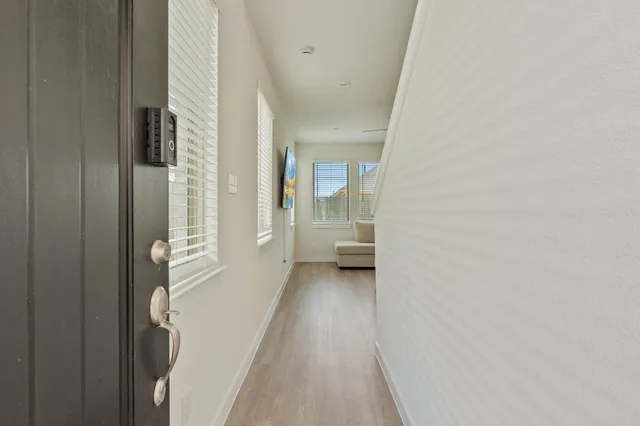 a view of a hallway with wooden floor and a bathroom