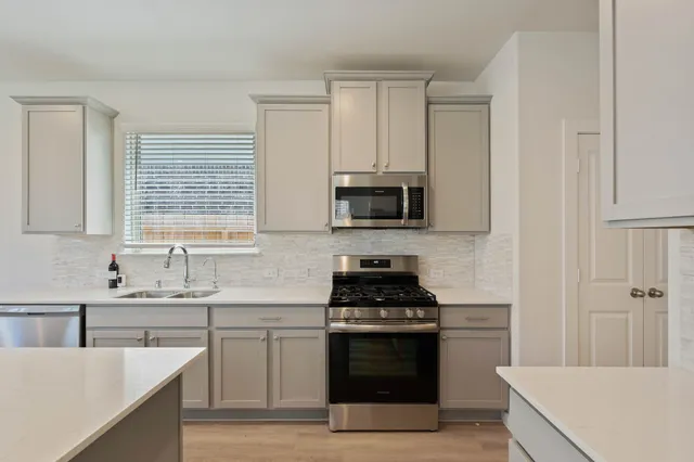 a kitchen with stainless steel appliances a stove sink microwave and cabinets