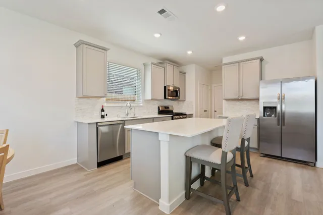 a kitchen with a sink stainless steel appliances and white cabinets