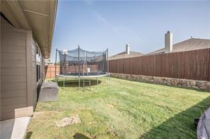 1409 Rosson Road Little Elm, TX 75068 - Photo 34 of 34 Expansive backyard featuring a green lawn, wood privacy fencing, and a stone retaining wall