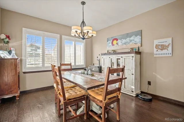 a dining room with wooden floor a chandelier a wooden table and chairs