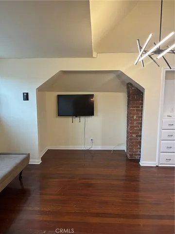 a view of an empty room with wooden floor and a ceiling fan