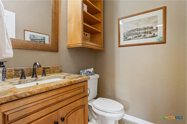 a bathroom with a granite countertop sink mirror vanity and toilet