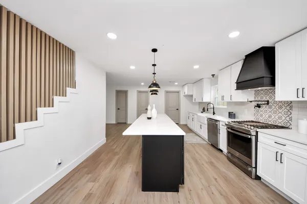 a large kitchen with stainless steel appliances granite countertop a stove a sink dishwasher and a refrigerator with wooden floor