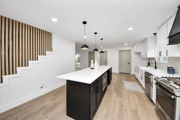 a large kitchen with stainless steel appliances a sink dishwasher and a refrigerator